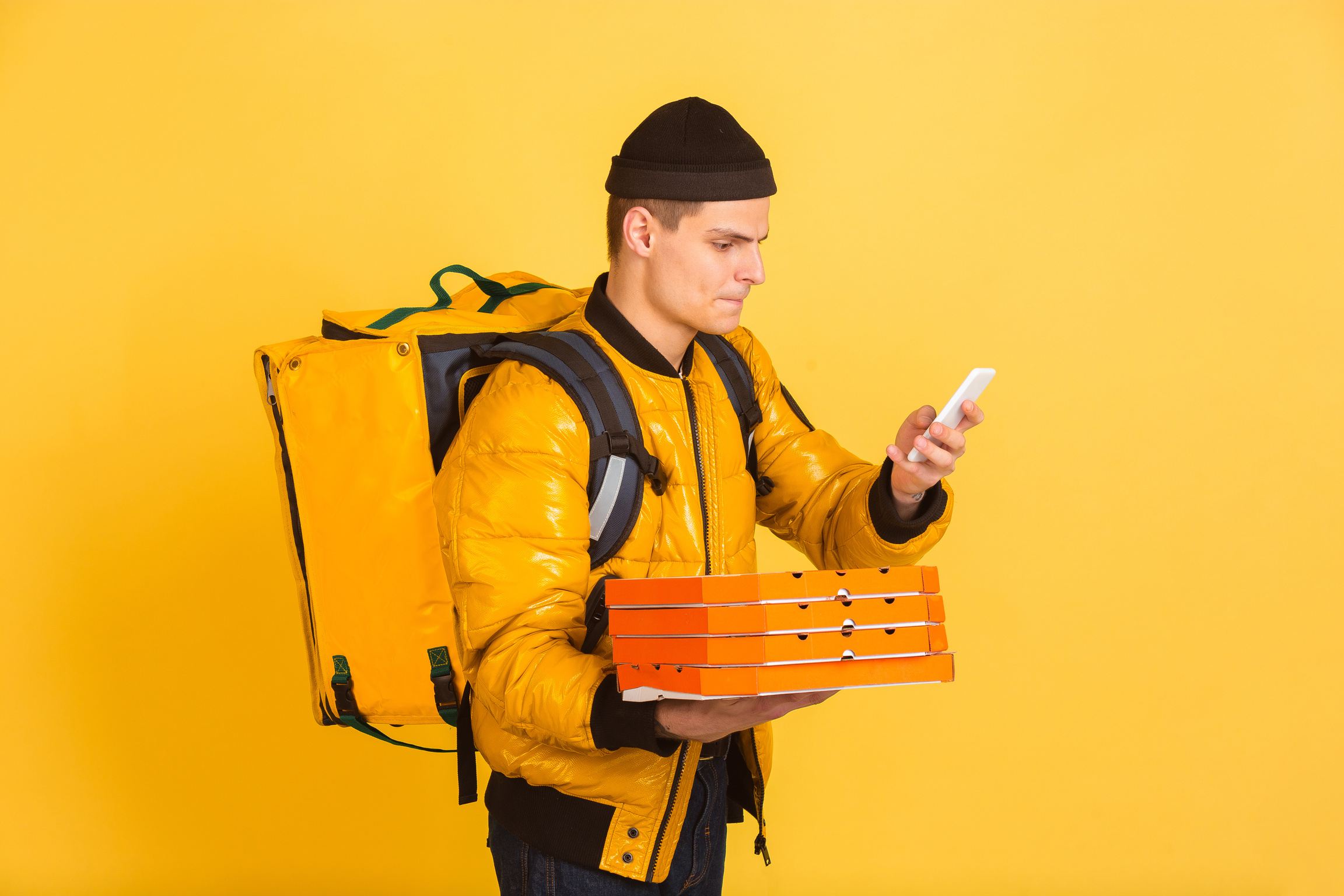 Pizza Delivery Man with Smartphone Isolated on Yellow Background